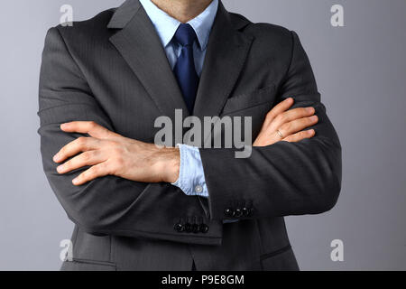 Unternehmer Stehen mit verschränkten Armen auf grauem Hintergrund Stockfoto