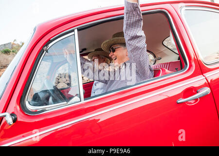 Paar od Älterer Reisender enjoyinmg die Reise auf einem alten Vintage rotes Auto. Glück und alternativer Lebensstil im Sommer Urlaub. nach Mann und Frau tog Stockfoto