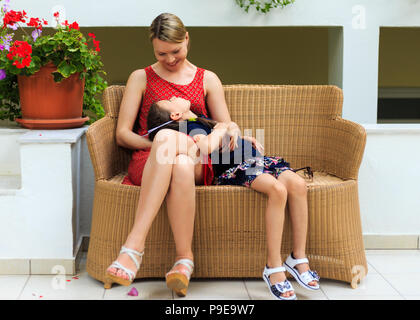 Mutter und Tochter sitzen in einer rattan Stuhl eines mediterranen Hotel Stockfoto