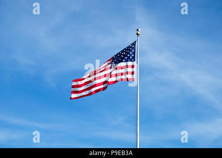 Amerikanische Flagge gehisst auf einem Mast mit negativen Raum und blauer Himmel Stockfoto