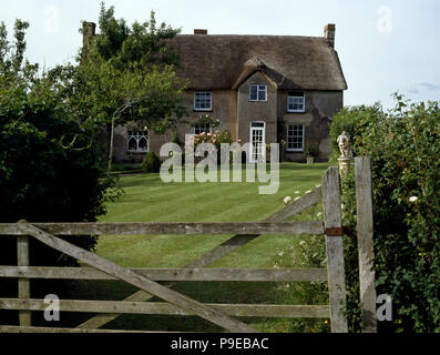 Fünf Balken Tor und frisch gemähtem Rasen vor reetgedeckten Landhaus Stockfoto