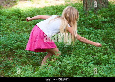 Kind blond adorable girl Kommissionierung frische Beeren auf blueberry Feld im Wald. Kind abholen Heidelbeeren im Wald. Kleine süße Mädchen spielen im Freien. Su Stockfoto