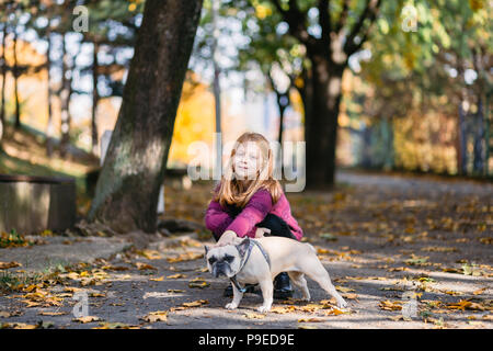 Schöne rothaarige Mädchen genießen Herbst Tag in einem Park mit ihren Französische Bulldogge Welpen. Stockfoto