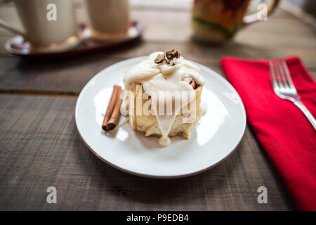 Nahaufnahme von einem einzigen Cinnamon Roll mit viel Zuckerguss Stockfoto