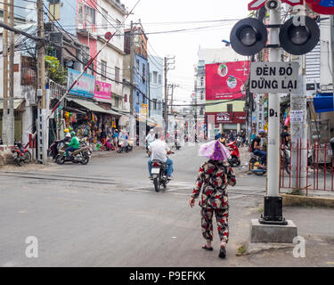 Eine vietnamesische Frau und ein Motorradfahrer im Norden überqueren - South Railway Line Überfahrt in Ho Chi Minh City, Vietnam. Stockfoto