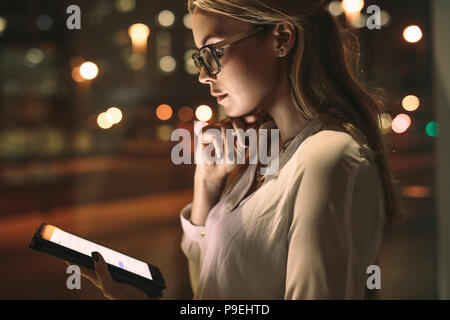 Die Frau, die in ihrem Büro kabine und Blick auf einen Tablet-PC. Seitenansicht der Frau an einem Tablet-PC suchen. Stockfoto