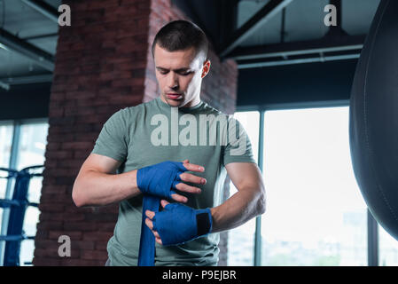 Dunkelhaarige Boxer mit Handgelenk wickelt in der Turnhalle Stockfoto