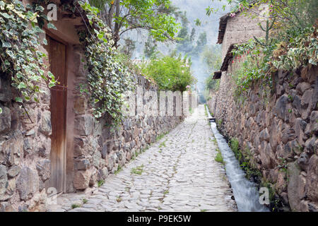 Atmosphärische schmale Straße mit Kopfsteinpflaster mit Adobe Häuser, Wasser Kanal gegen die Wand im historischen Anden Stadt Cusco, Sacred Valley läuft Stockfoto