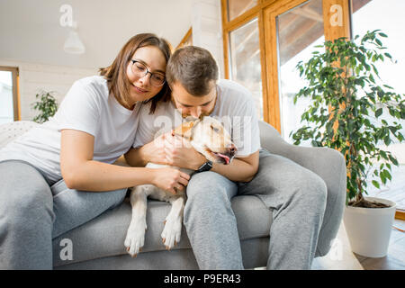 Paar mit Hund auf der Couch zu Hause Stockfoto