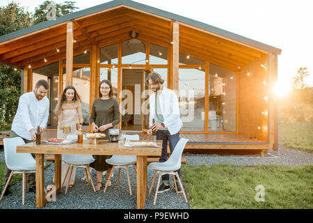 Freunde die Vorbereitung für das Abendessen in der Nähe des Hauses Stockfoto