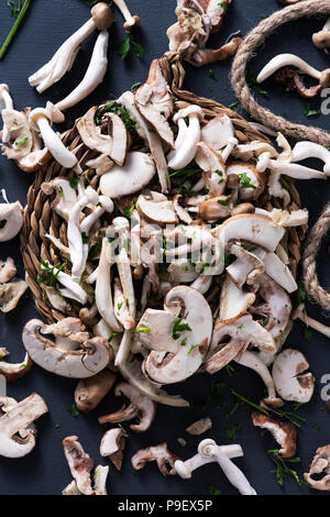 Hohe Betrachtungswinkel von einem Stapel von Raw gemischte Pilze, wie z. B. gemeinsame Champignons, Austernpilze und Shiitake, auf einem grauen rustikalen Holztisch Stockfoto
