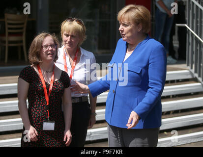 Deutschland, Köln. 18 Juli, 2018. Die deutsche Bundeskanzlerin Angela Merkel (R, CDU) besucht das Caritas Zentrum Kalk und ist von Natalie Dedreux (L) begrüßt. In der Mitte steht Michaela Dedreux, Mutter von Natalie. Das Mädchen mit Down Syndrom forderte die Kanzlerin eine Frage während der Wahlkampagne in Bezug auf das Recht auf Schwangerschaftsabbruch. Credit: Oliver Berg/dpa/Alamy leben Nachrichten Stockfoto