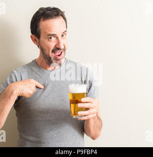 Ältere Menschen trinken Bier mit Überraschung Gesicht zeigenden Finger zu sich selbst Stockfoto