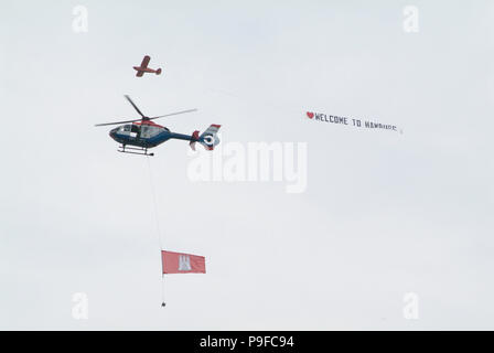 Einmotoriges Flugzeug zieht ein Werbebanner über den Hamburger Hafen: WILLKOMMEN IN HAMBURG. Davor ein polizei-hubschrauber mit großer Hamburg-Flagge Stockfoto