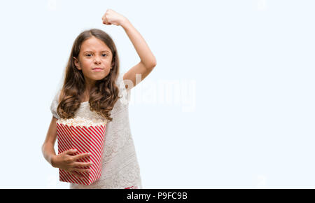 Brunette hispanische Mädchen essen Popcorn genervt und frustriert schrie mit Zorn, verrückt und schreien mit erhobener Hand, Wut Konzept Stockfoto