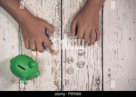 Die Hände des Jungen Zählen von Münzen aus seinem Sparschwein. Stockfoto