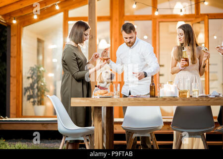 Freunde mit Hund essen in der Nähe des Hauses Stockfoto