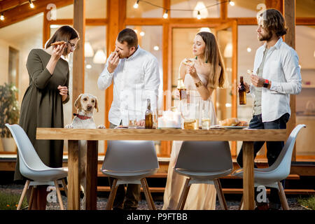 Freunde mit Hund essen in der Nähe des Hauses Stockfoto