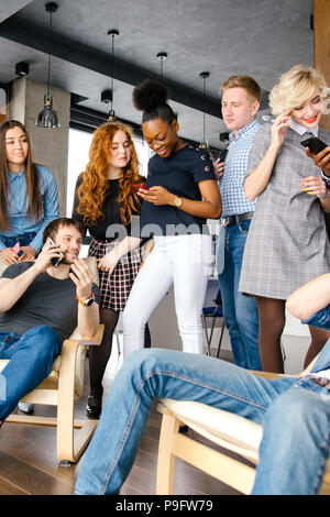 Junge afrikanische Frauen ist gerade lustige Video auf Handy während in den überfüllten Raum stehen Stockfoto
