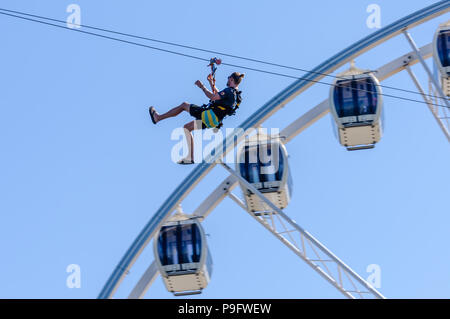 Ein Mann zip-Linien hinter einem Riesenrad am Strand von Scheveningen, Den Haag, Niederlande. Stockfoto