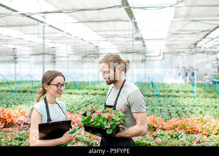 Arbeitnehmer mit Blumen im Gewächshaus Stockfoto