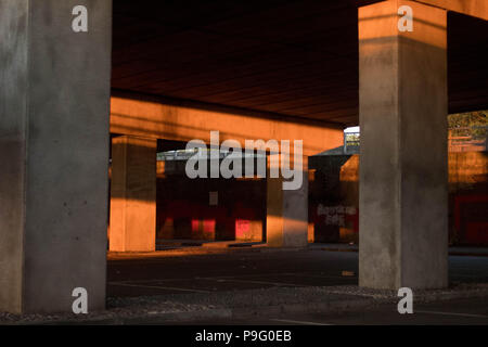 Urban Decay - residuale Sonnenlicht & Farbe in einen leeren Parkplatz unter einer Überführung. Essex, Großbritannien. Stockfoto