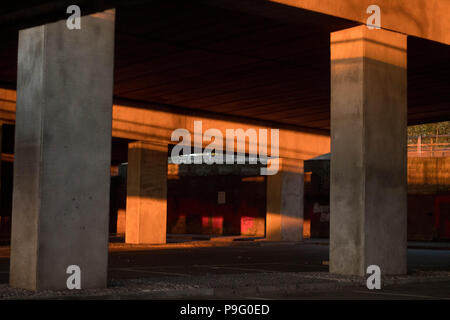 Urban Decay - residuale Sonnenlicht & Farbe in einen leeren Parkplatz unter einer Überführung. Essex, Großbritannien. Stockfoto