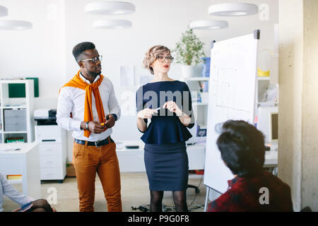 Junge kaukasier attraktive Trainer in Gläser gibt Kurs für Mitarbeiter in der Nähe der Tafel im Innenbereich Stockfoto