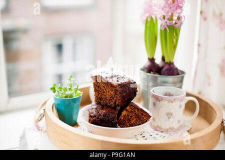Chocolate Cupcake mit Zucker und Kaffee. Frühstück auf ein Tablett aus Holz und Blumen. Blick aus dem Fenster auf die Stadt. Freier Platz für Text oder eine Postkarte. Stockfoto
