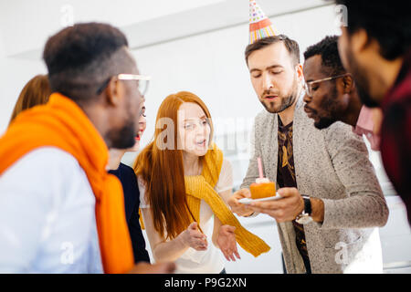 United Team, bläst die Kerze auf Kuchen. nach oben Bild schließen Stockfoto