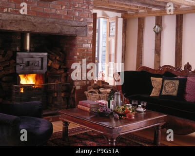 Holzofen in 90er Jahre Ferienhaus Wohnzimmer mit antiken Sofa Stockfoto