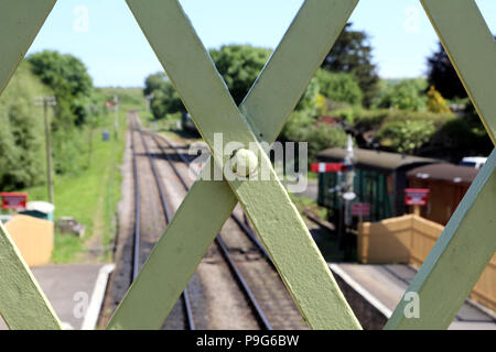 Nahaufnahme der Schmiedearbeiten einer alten Eisenbahn Brücke, mit Track, Plattform, Signale und Fahrzeuge in den unscharfen Hintergrund, auf einem sonnigen Sommer da Stockfoto