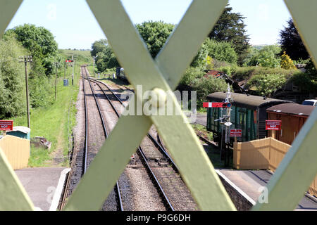 Bahn, Plattform, Signale und Fahrzeuge im Hintergrund, auf einem sonnigen Sommertag, durch die der Fokus Schmiedearbeiten eines alten Victoria gesehen Stockfoto