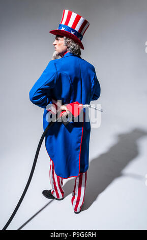 Uncle Sam-Figur von hinten mit einem Benzin pumpe nozzel hinter seinem Rücken gesehen. Stockfoto