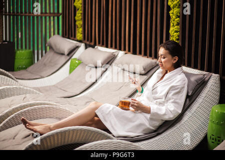 Die seitliche Ansicht Portrait von Brünette mit Freunden chatten in der Toilette schließen. Sehen Sie sich die Fotos an. Blick auf den Bildschirm Stockfoto