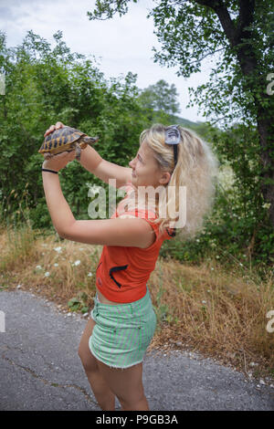 Mädchen halten sich die Schildkröte auf der Straße Stockfoto