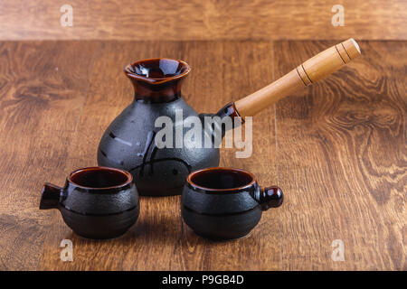 Ton turka und zwei Tassen Kaffee auf einem Holztisch Stockfoto