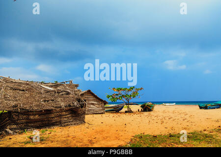 Reetgedeckte coconut Leaf House oder Fischerhütte und Boote auf tropischen Strand. Traditionelle oder Vintage eco-freundliches Zuhause in ländlichen Dorf Stockfoto