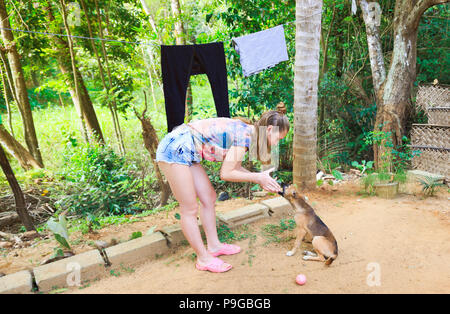 Junges Mädchen spielt mit den Welpen außerhalb, Mensch und Hund Freundschaft im grünen Hof Stockfoto