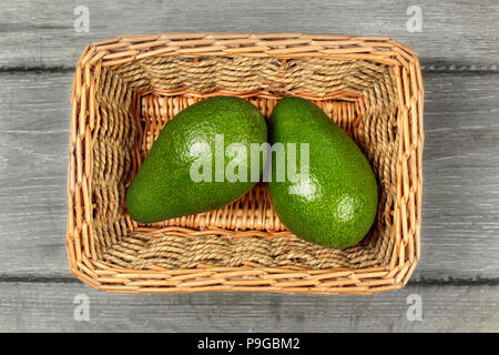 Table Top - zwei ganze avocado Birnen in rechteckiger Korb. Stockfoto