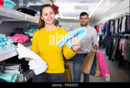 Gerne fröhliche positive junge Frau Wahl neue Handtücher in Store beim Einkaufen mit meinem Mann Stockfoto