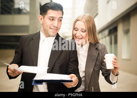 Geschäftsfrau mit Ihrem Mitarbeiter sind Kaffee trinken und Lesen von Dokumenten vor der Unterzeichnung im Freien. Stockfoto