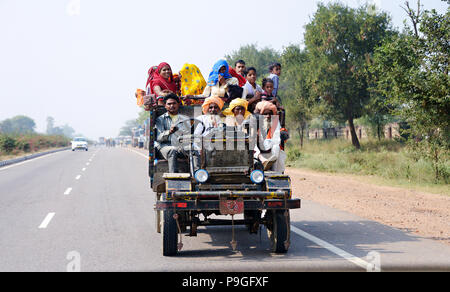 Straße Szenen des realen Lebens in Delhi Indien, fotografiert aus einem fahrenden Auto. Eine große indische Familie, die zusammen Reisen auf einem alten Open gekrönt. Stockfoto