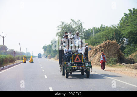 Straße Szenen des realen Lebens in Delhi Indien, fotografiert aus einem fahrenden Auto. Eine große indische Familie, die zusammen Reisen auf einem alten Open gekrönt. Stockfoto