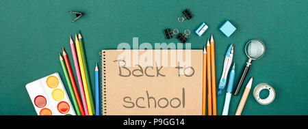 Der Schüler Schreibtisch mit stationären und Notebook mit Inschrift Zurück zu Schule auf grünem Hintergrund. Vorbereitung auf die Schule. Banner für die Website. Stockfoto