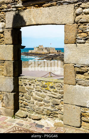 Das Fort National auf die Gezeiten Insel mit der französischen Flagge im Wind durch einen steinernen Tür von der Stadt Saint-Malo in der Bretagne gesehen weht. Stockfoto