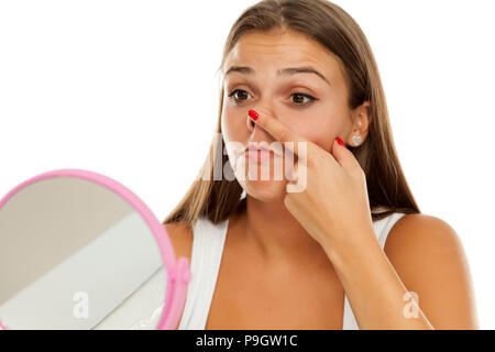 Junge Frau von sich selbst im Spiegel zu betrachten und Ihre Nase berühren. Stockfoto