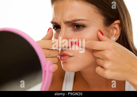 Junge Frau von sich selbst in den Spiegel schauen und quetschen Pimples Stockfoto