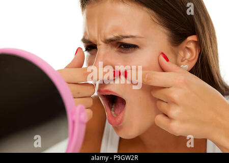 Junge Frau von sich selbst in den Spiegel schauen und quetschen Pimples Stockfoto