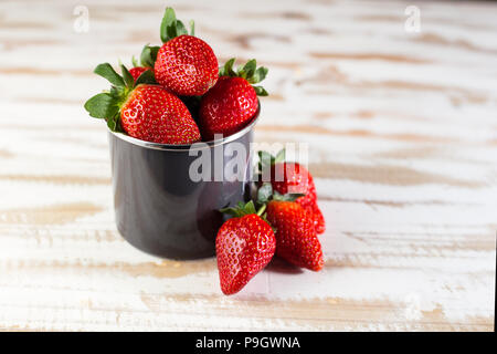 Erdbeeren in grau Emaille Tasse auf weißen Oberfläche Holz, gesundes Essen. Stockfoto